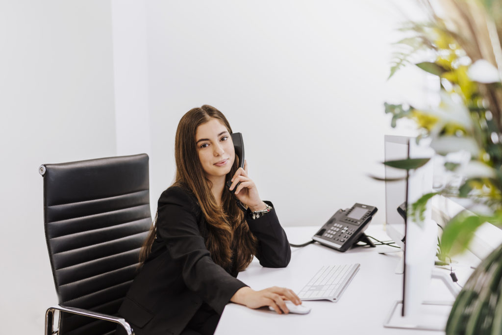 Immobilienmaklerin telefoniert am Arbeitsplatz