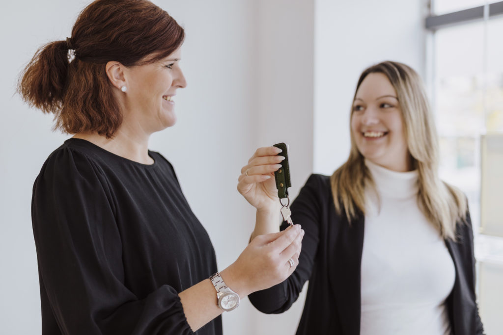 Frau überreicht Maklerin die Haustürschlüssel